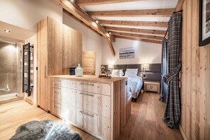 A bedroom with a wooden ceiling, a bed, a bedside table, and a nightstand. - Snowdust – Warm & Welcoming Stay in Megève (Megeve)