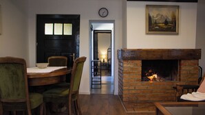 Una sala de estar acogedora con chimenea de ladrillo, un comedor con muebles de madera y un pasillo que conduce a otra habitación.