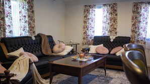 Una sala de estar con dos sofás de cuero oscuro, una mesa de centro de vidrio y una mesita auxiliar con una tetera.