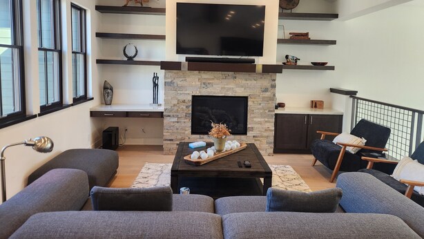 A modern living room with a stone fireplace, a flat-screen TV, and a large sofa. - Snowcreek Resort Vacation Rental 1543 (Mammoth Lakes)