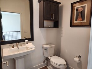 Une salle de bain avec un lavabo blanc, des toilettes et une œuvre d’art encadrée accrochée au mur.