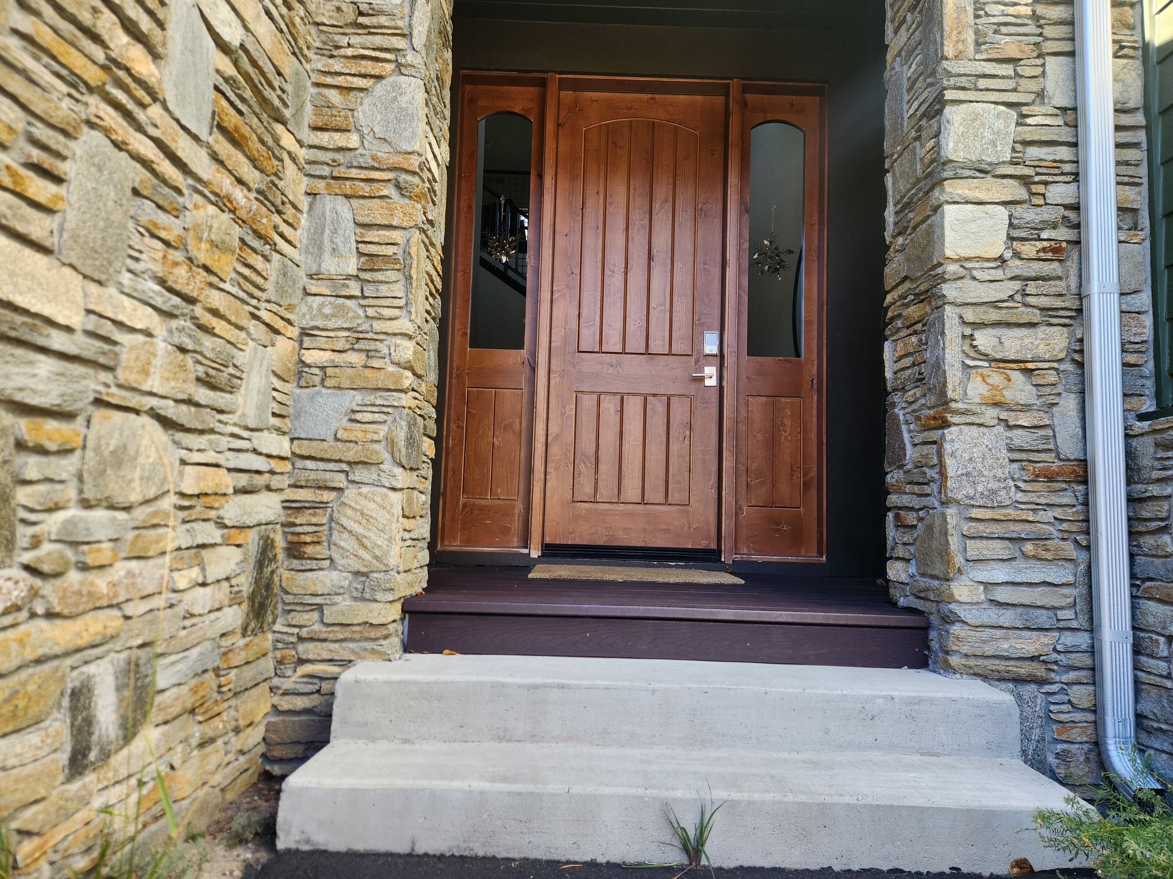 A stone building with a wooden double door and concrete steps leading to a dark entrance.