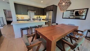 Une cuisine moderne avec des meubles de couleur sombre, un îlot central et des tabourets de bar.