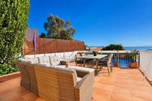 A terrace with wicker furniture, a pool, and a view of the sea. - Villa Maria de Bonaire (Mallorca)