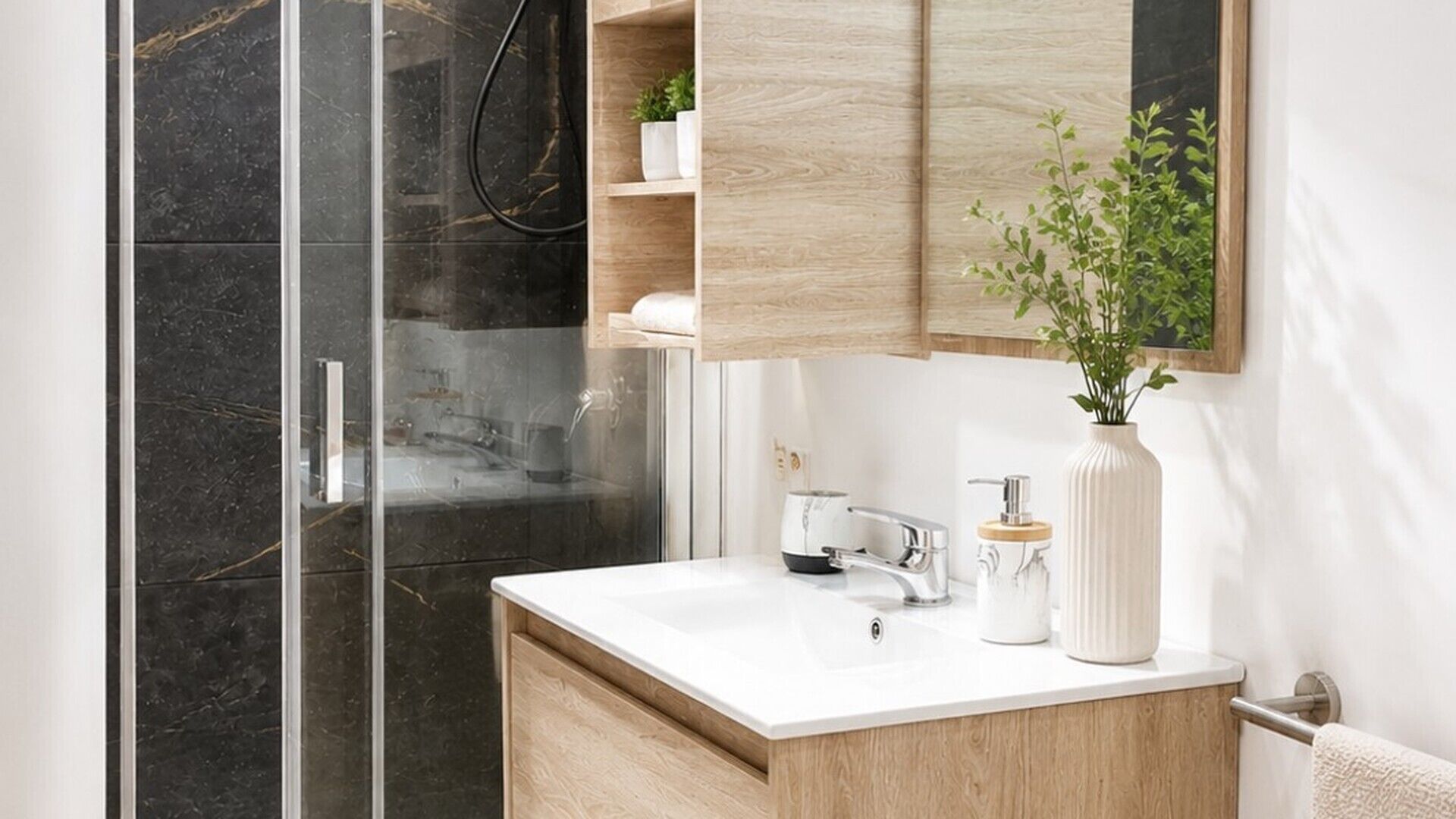 A modern bathroom with a glass shower enclosure, a white sink, and a wooden vanity.