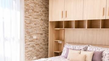 A bedroom with a bed, a wooden wardrobe, and a brick wall.