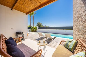 A covered outdoor area with wicker furniture, a pool, and a view of the sea. - Villa Salty Sun 5 - Two Bedroom Villa, Sleeps 4 (Kremasti)