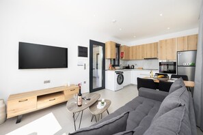 Un moderno appartamento con zona giorno, tavolo da pranzo, cucina e lavatrice e asciugatrice integrate.