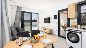 A modern kitchen with a washing machine, dining area with table set for two, and a view of the pool.