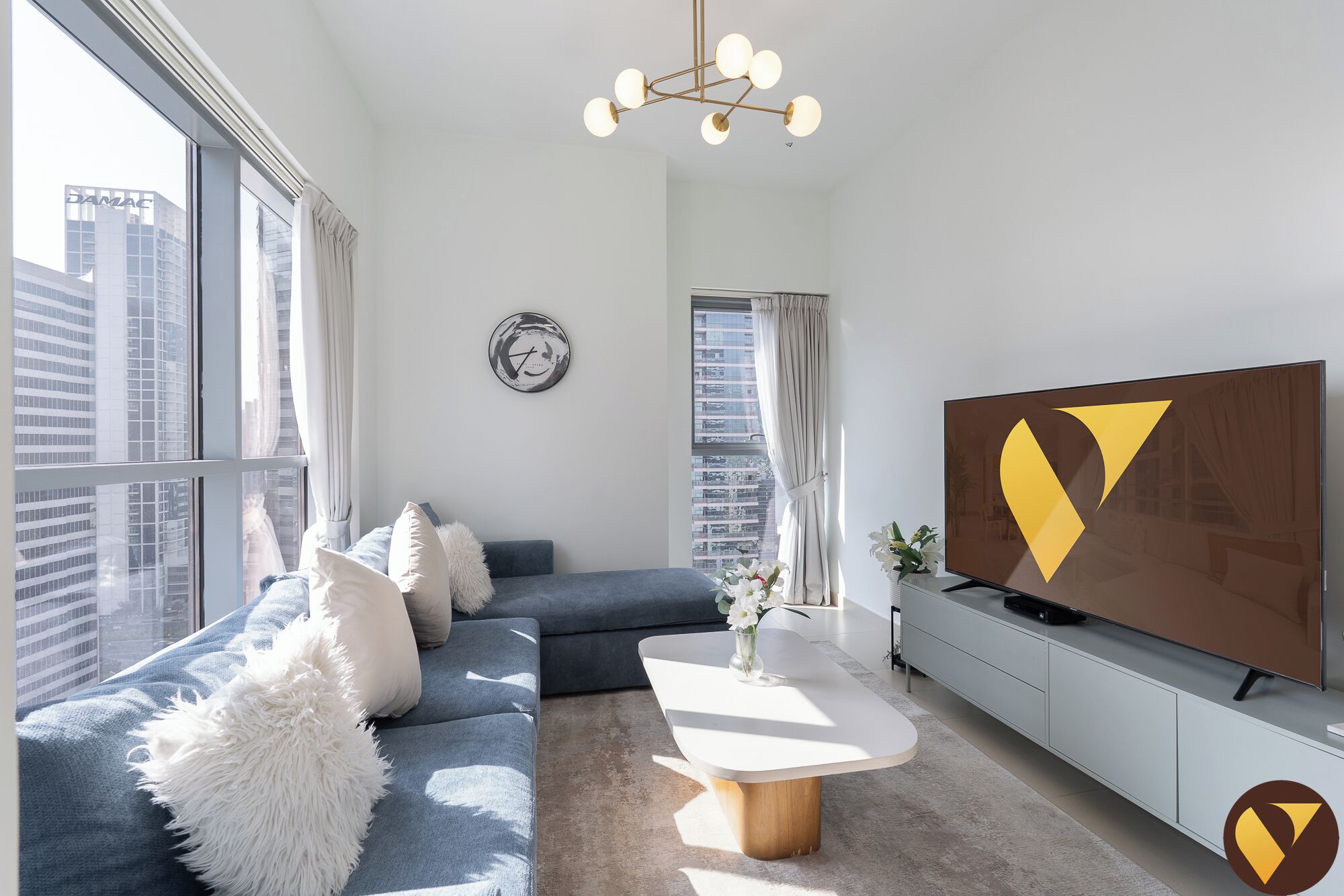 A modern living room with a sofa, a coffee table, a TV, and a city view.