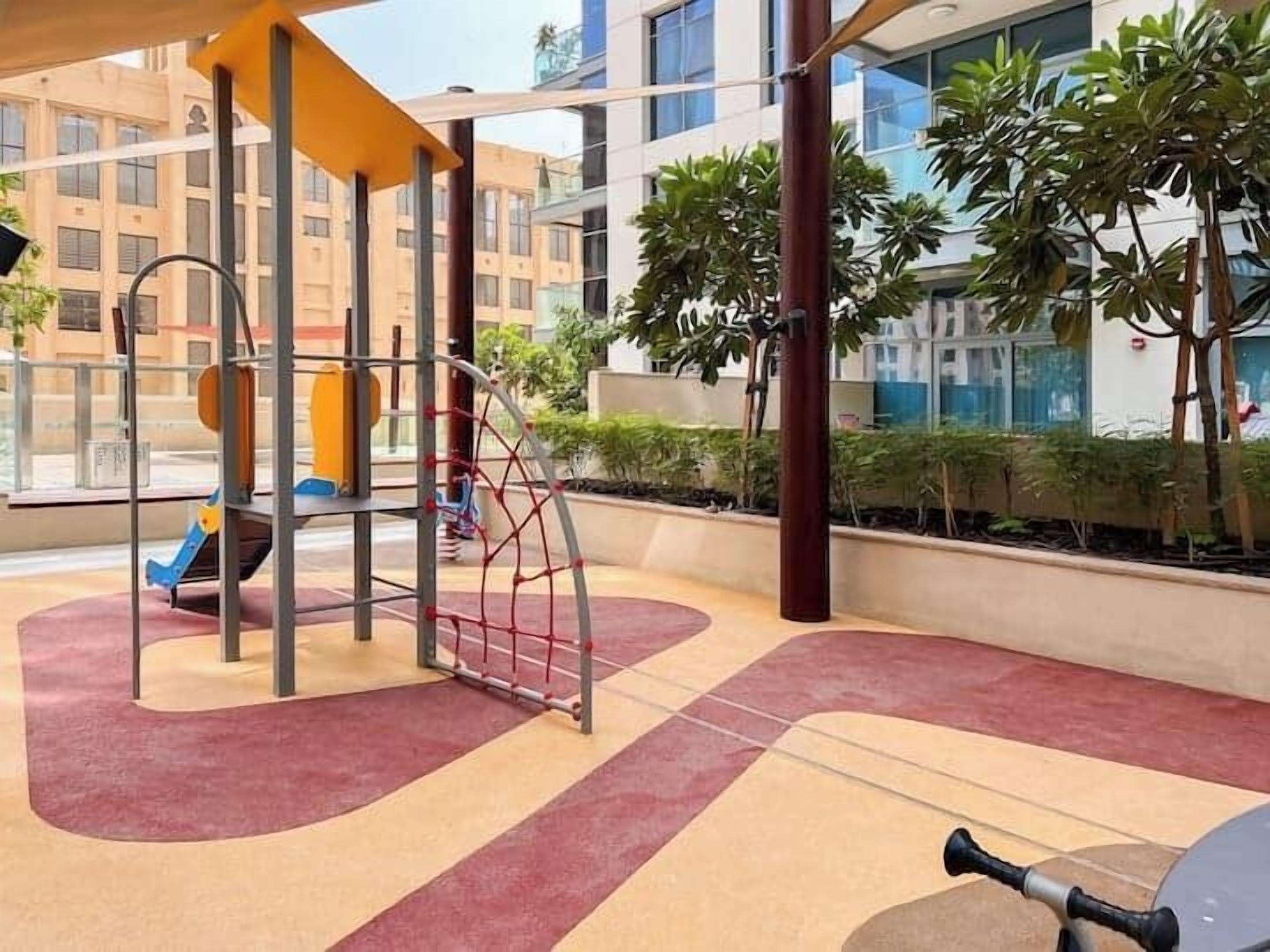 An outdoor play area with a climbing structure, a slide, and a swing set.