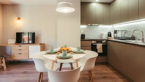 Een moderne keuken met een eethoek, met een ronde tafel met stoelen, een televisie en een koffiezetapparaat.
