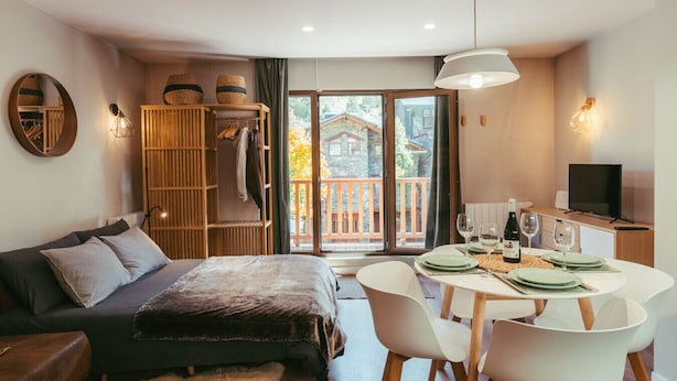 Een moderne slaapkamer met een bed, zithoek, eettafel voor twee personen en een televisie.