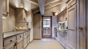 A narrow kitchen with wooden cabinets, a stone countertop, and a view through a glass door. - MONTCLAIR HOME - Four Bedroom Apartment, Sleeps 8 (Verbier)