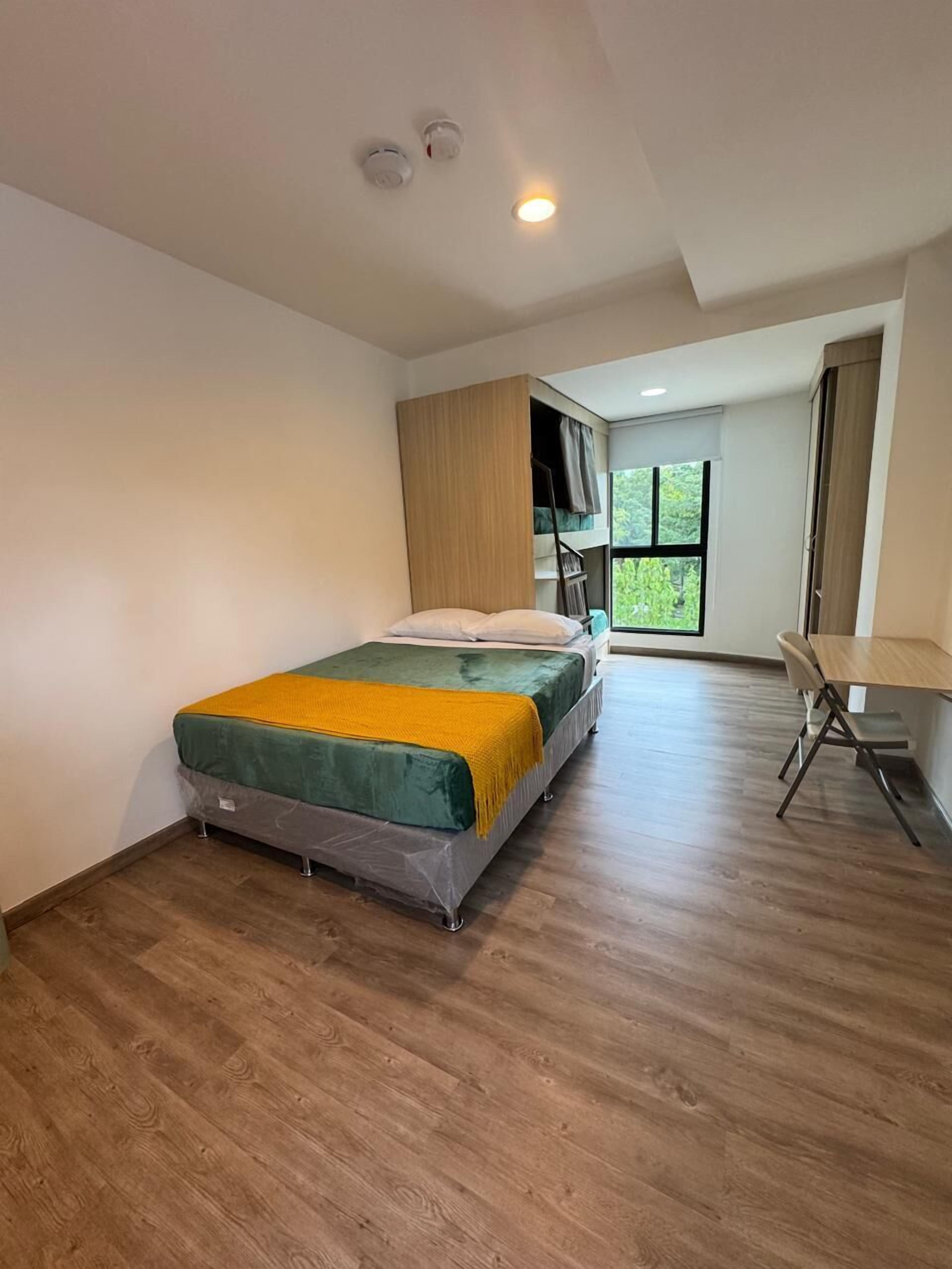 A modern bedroom with a bed, a desk, and a window.