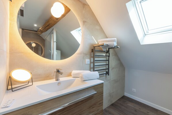 A modern bathroom with a large mirror, a sink, and a towel rack. - Hotel les Vents d'Anges (Beaune)