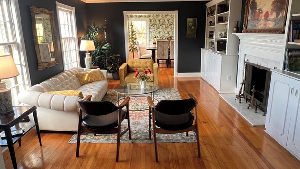 A living room with a white sofa, two black chairs, a glass coffee table, and a fireplace. - Massey's in the Park (Vicksburg)