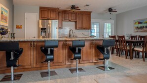 Une cuisine moderne avec des meubles en bois, un réfrigérateur en acier inoxydable et un coin bar avec des tabourets.
