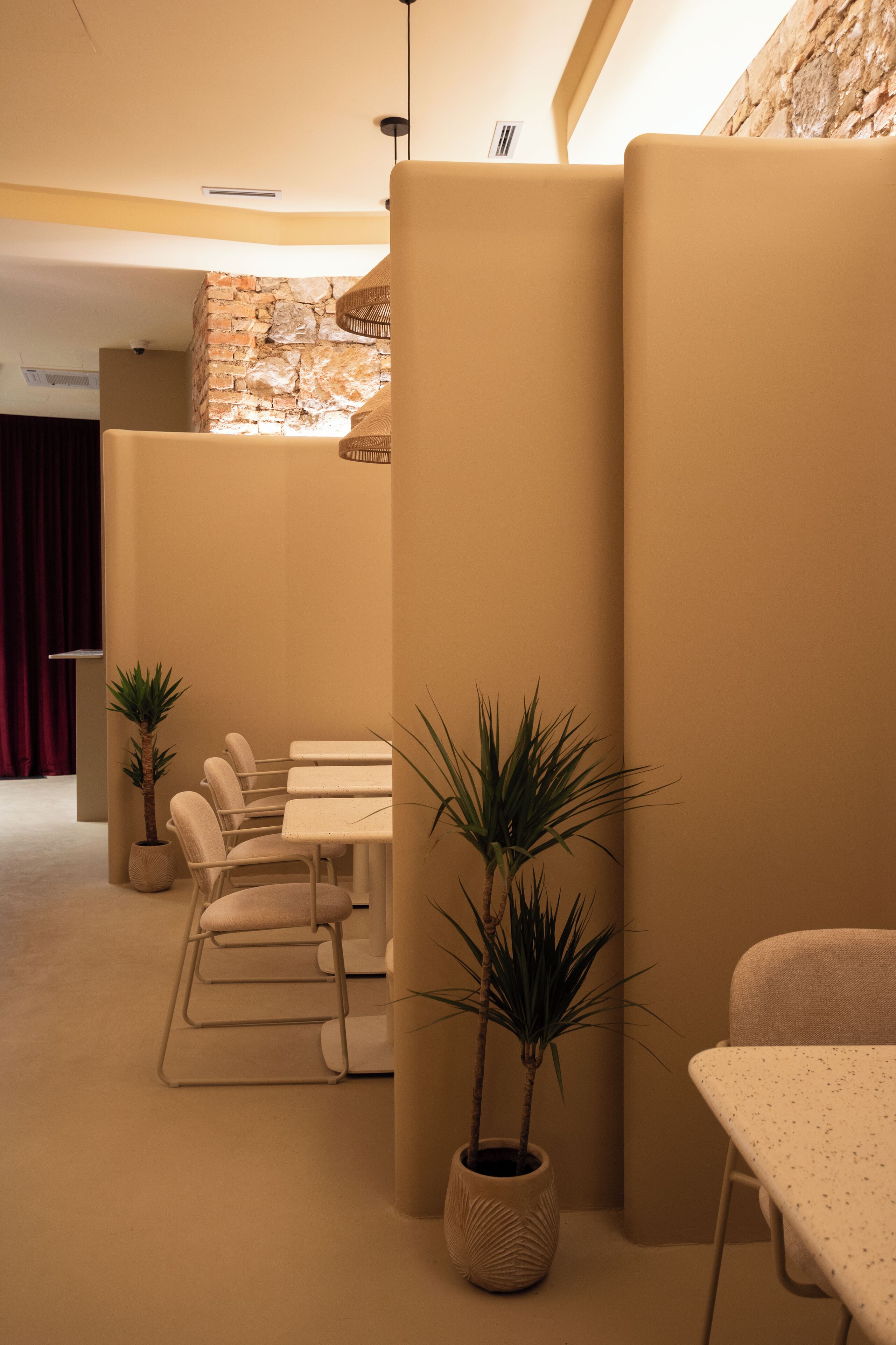 A modern interior with a stone wall, beige walls, and a seating area with tables and chairs.