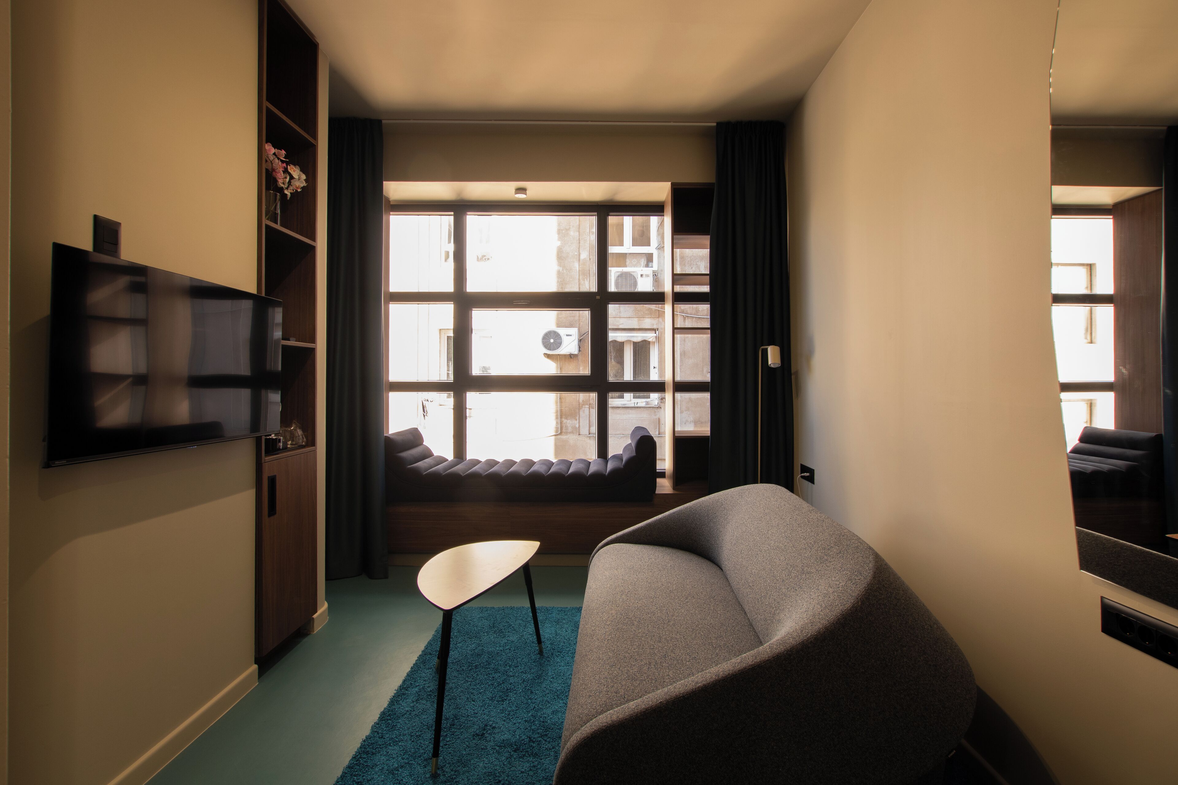 A modern living room with a large window, a flat-screen TV, a sofa, and a coffee table.