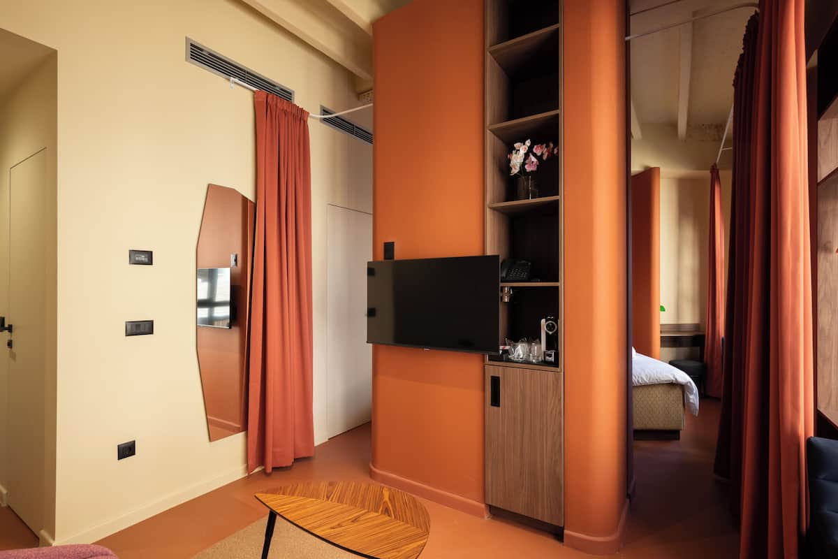 Une chambre d’hôtel moderne dotée d’un grand lit, d’un téléviseur à écran plat, d’une armoire en bois et d’un petit coin salon.