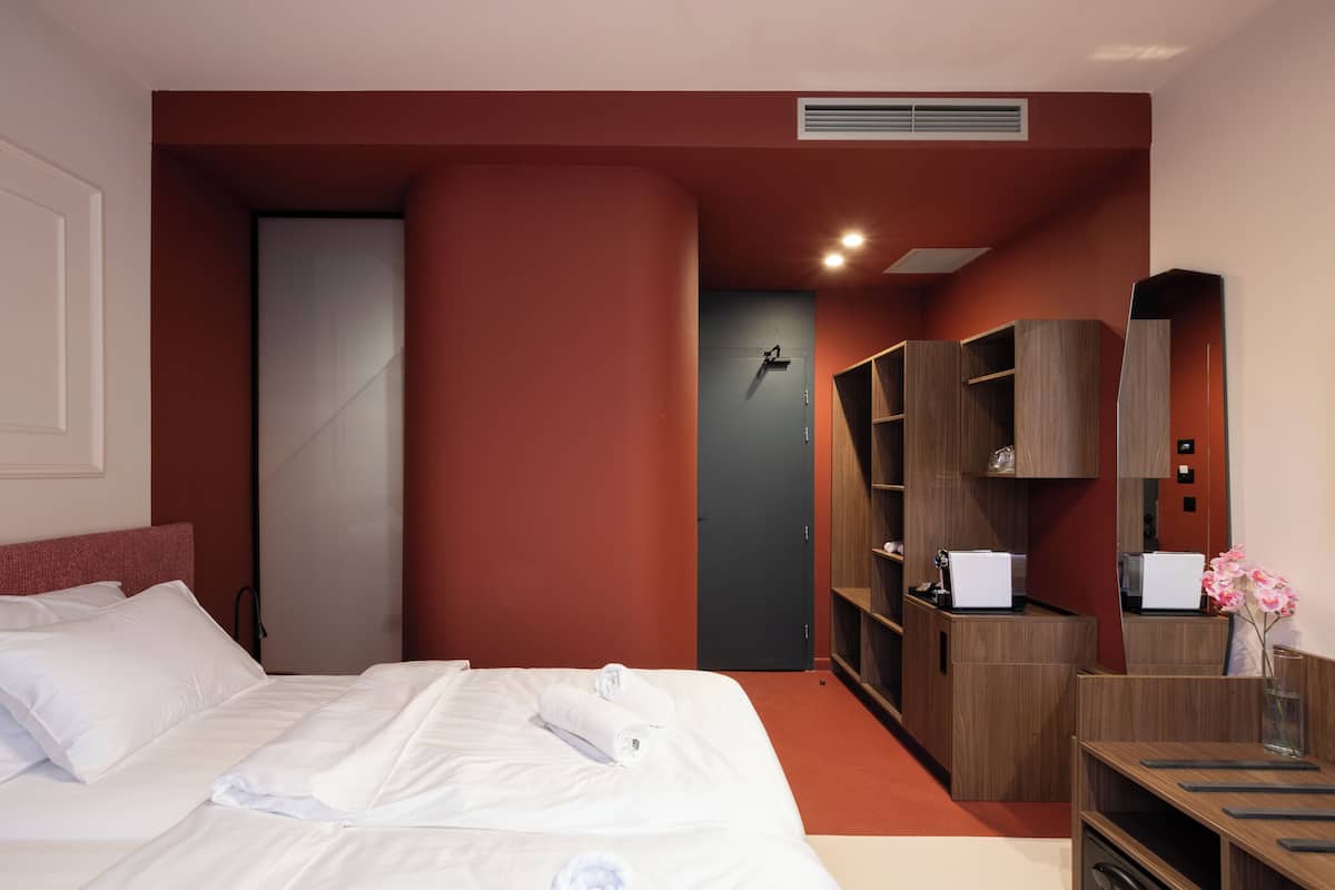 Une chambre d’hôtel avec un lit, un bureau et une armoire.