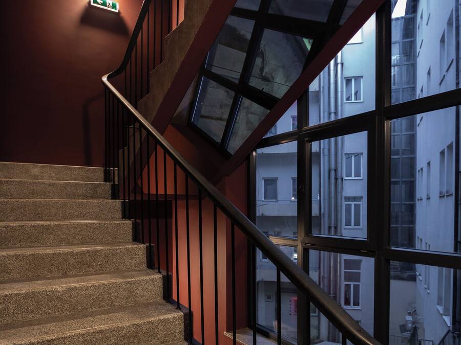 Eine Treppe mit Metallgeländer und Blick auf Gebäude durch große Fenster.