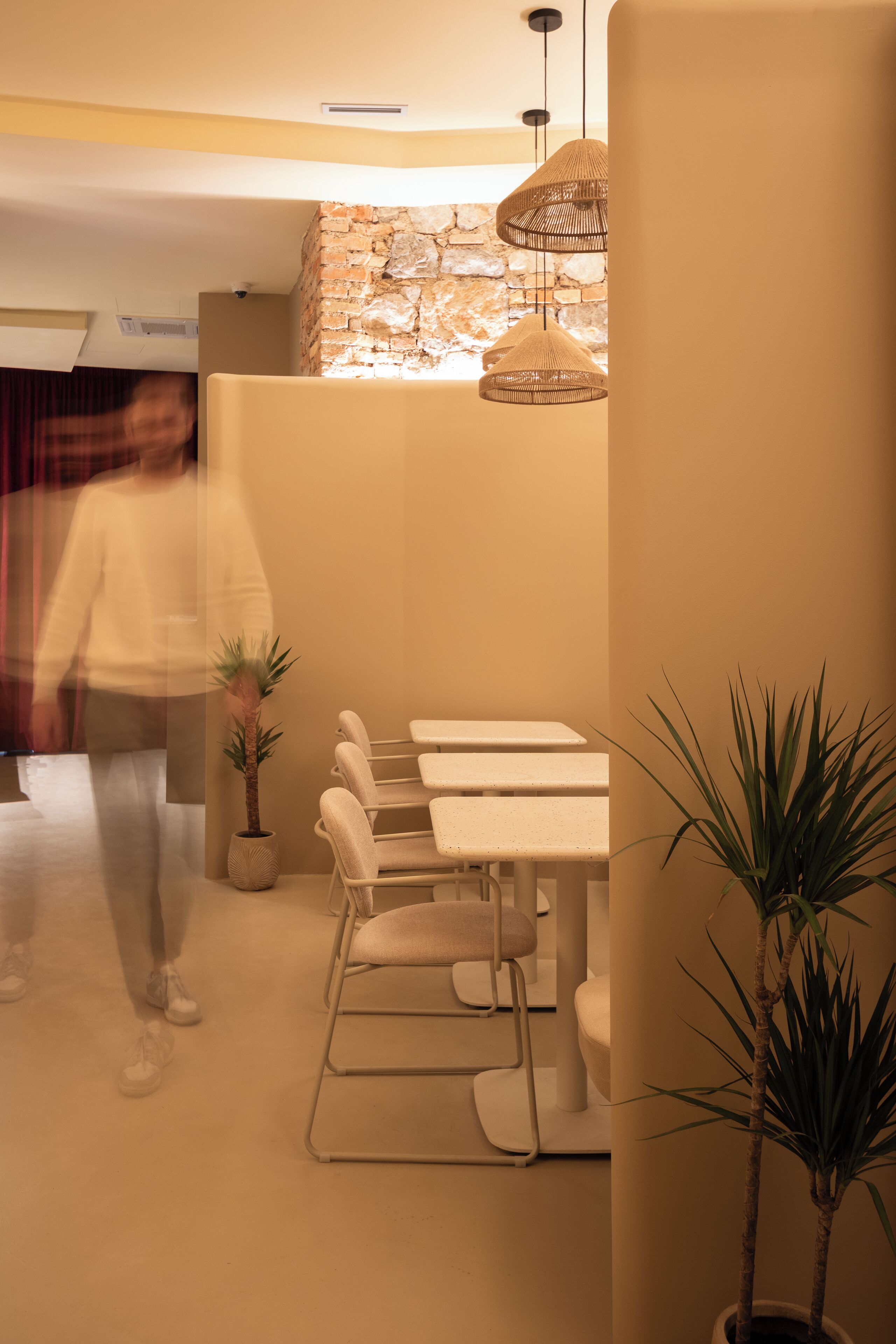 Een moderne eethoek met een bakstenen muur, hanglampen en een witte tafel met stoelen.