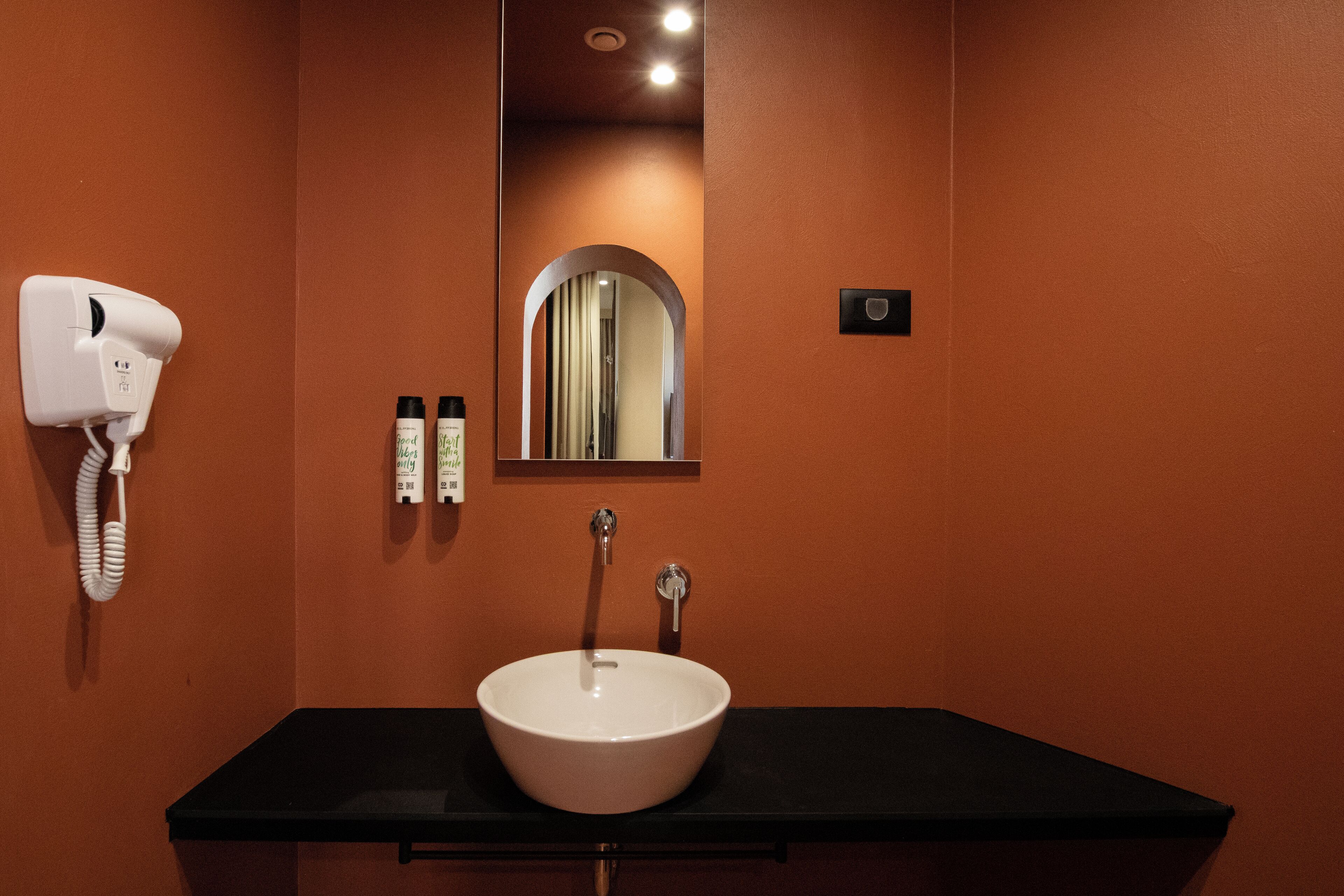 A bathroom with a white sink, a mirror, a hairdryer, and two bottles of lotion.