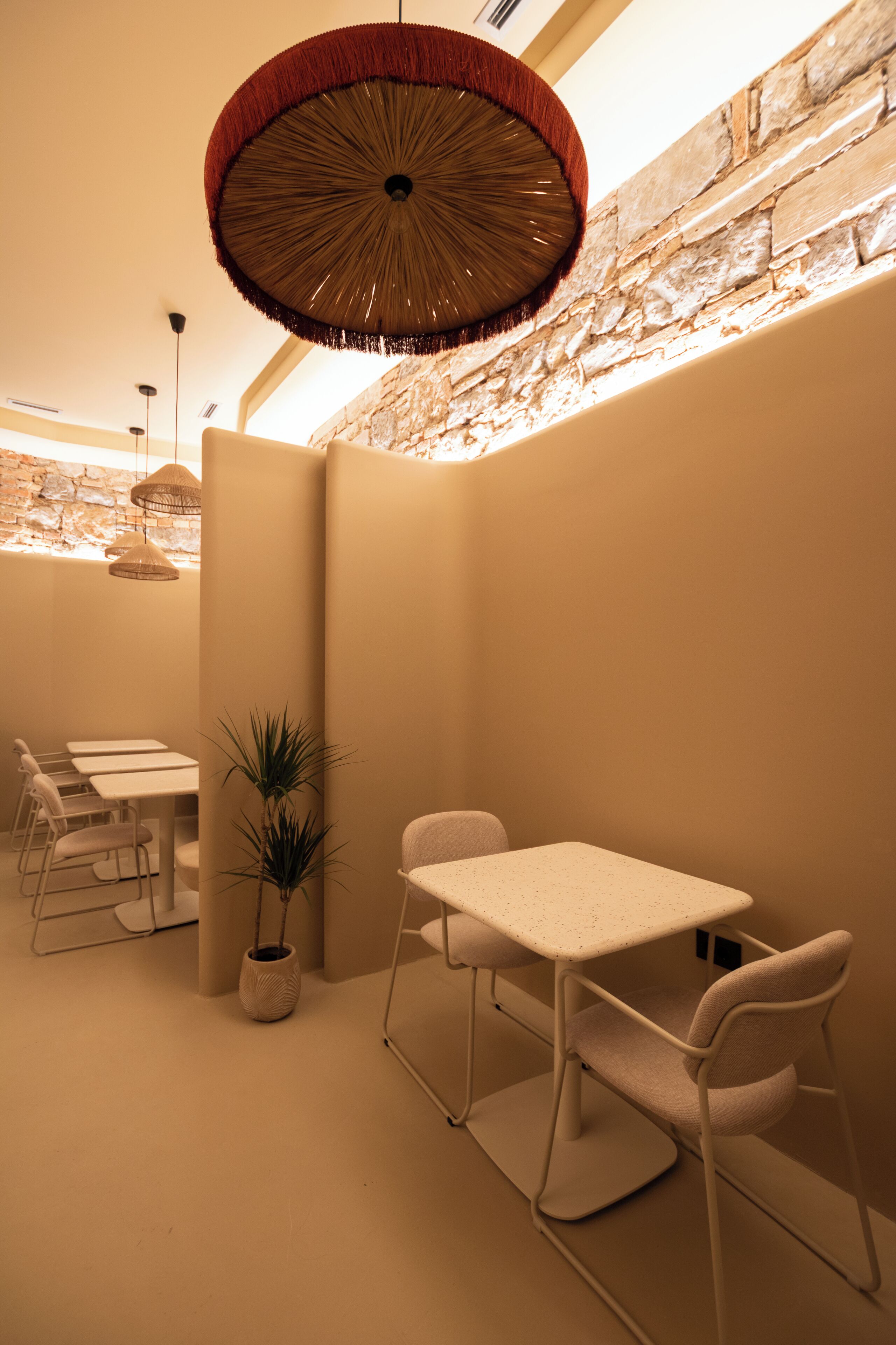 A modern interior with a dining area, a hanging light fixture, and a stone wall.