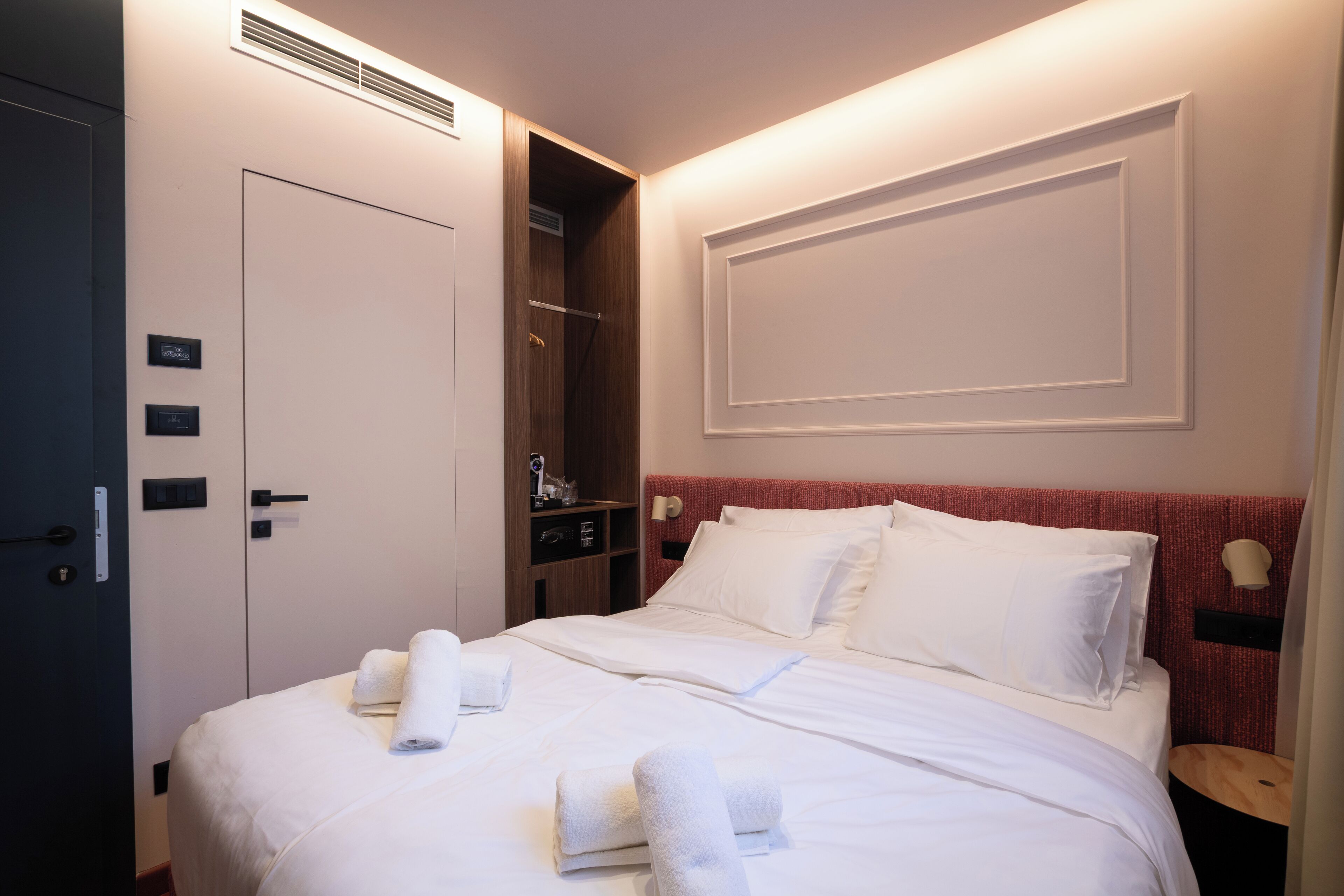 A hotel room with a neatly made bed, a wardrobe, and a shower area.