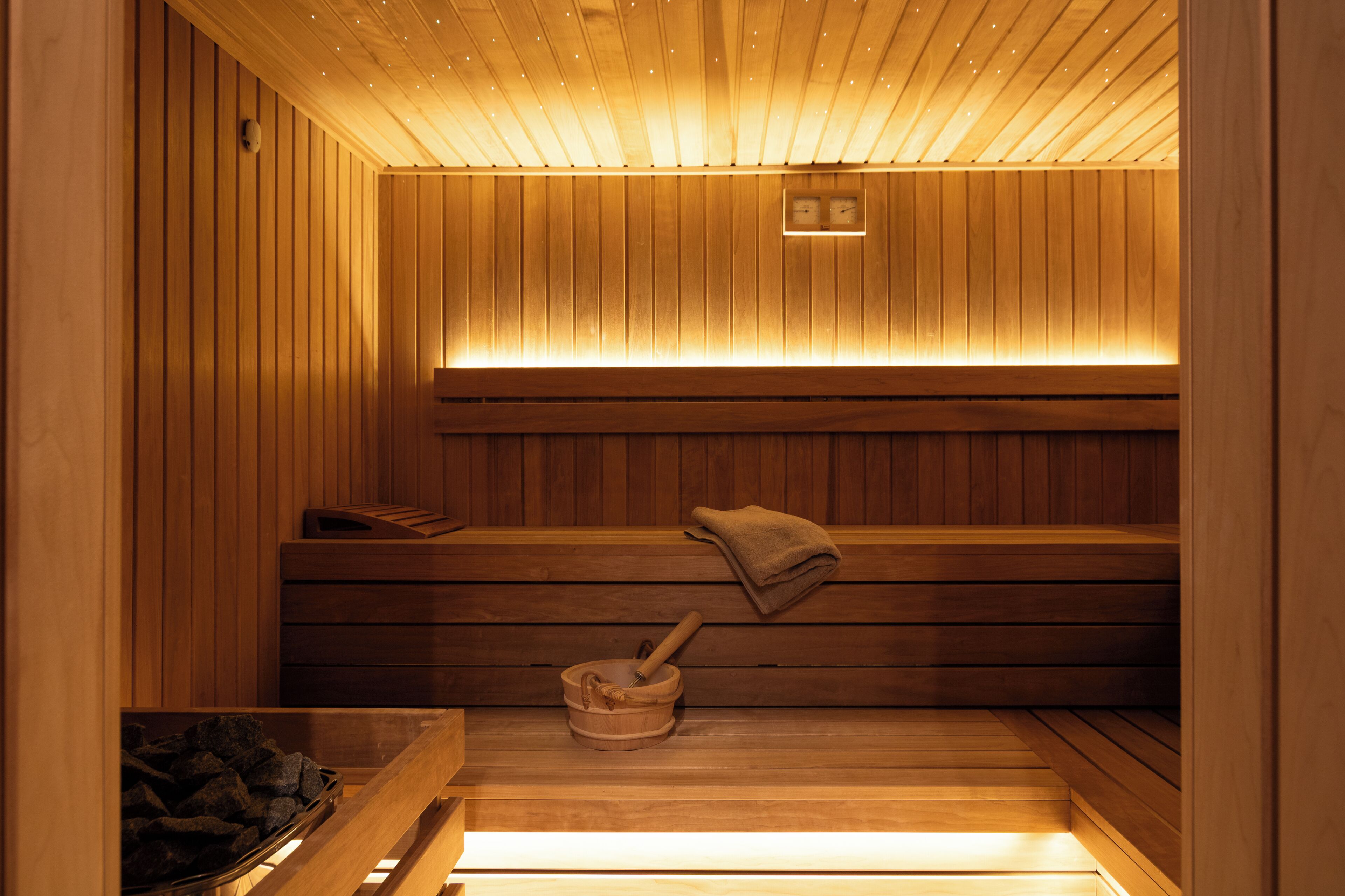Een sauna met houten banken, een bankverwarmer en een stenen wasbak.