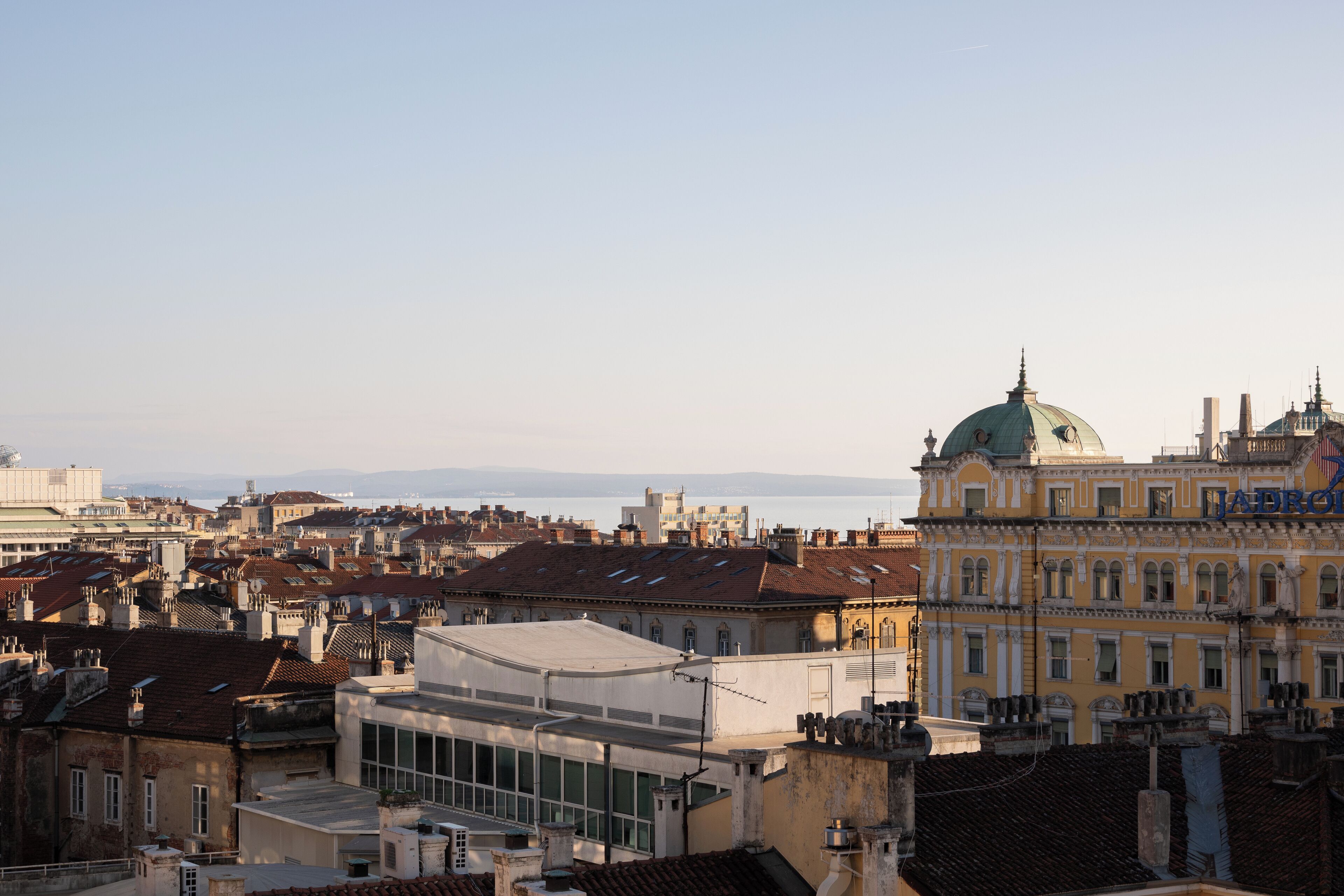 Une vue urbaine avec des bâtiments historiques, dont un bâtiment remarquable surmonté d’un dôme et une grande structure à fenêtres au premier plan.
