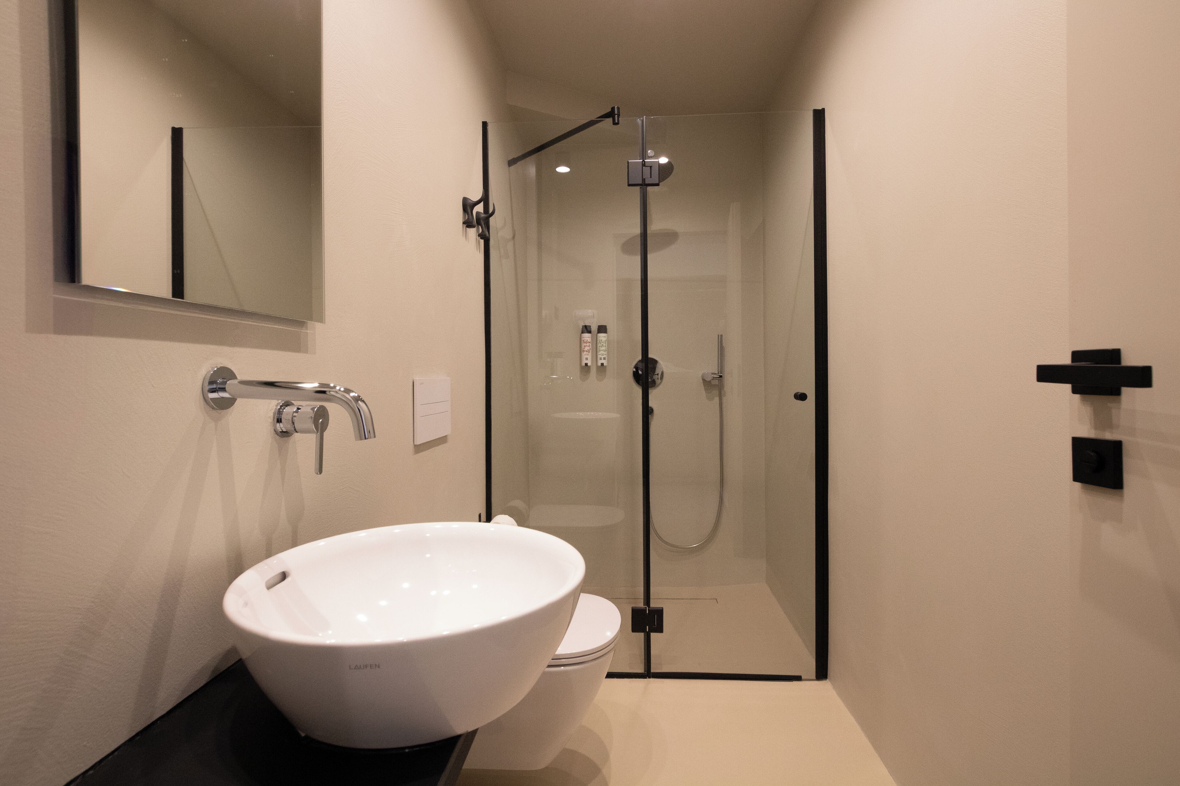 Une salle de bain moderne avec un lavabo blanc, des toilettes et une douche à parois de verre.