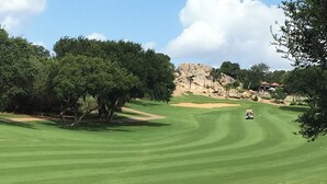 A golf course with a clear path, trees, and a distant rocky hill. - Designer Furnished Home Away from Home (Horseshoe Bay)