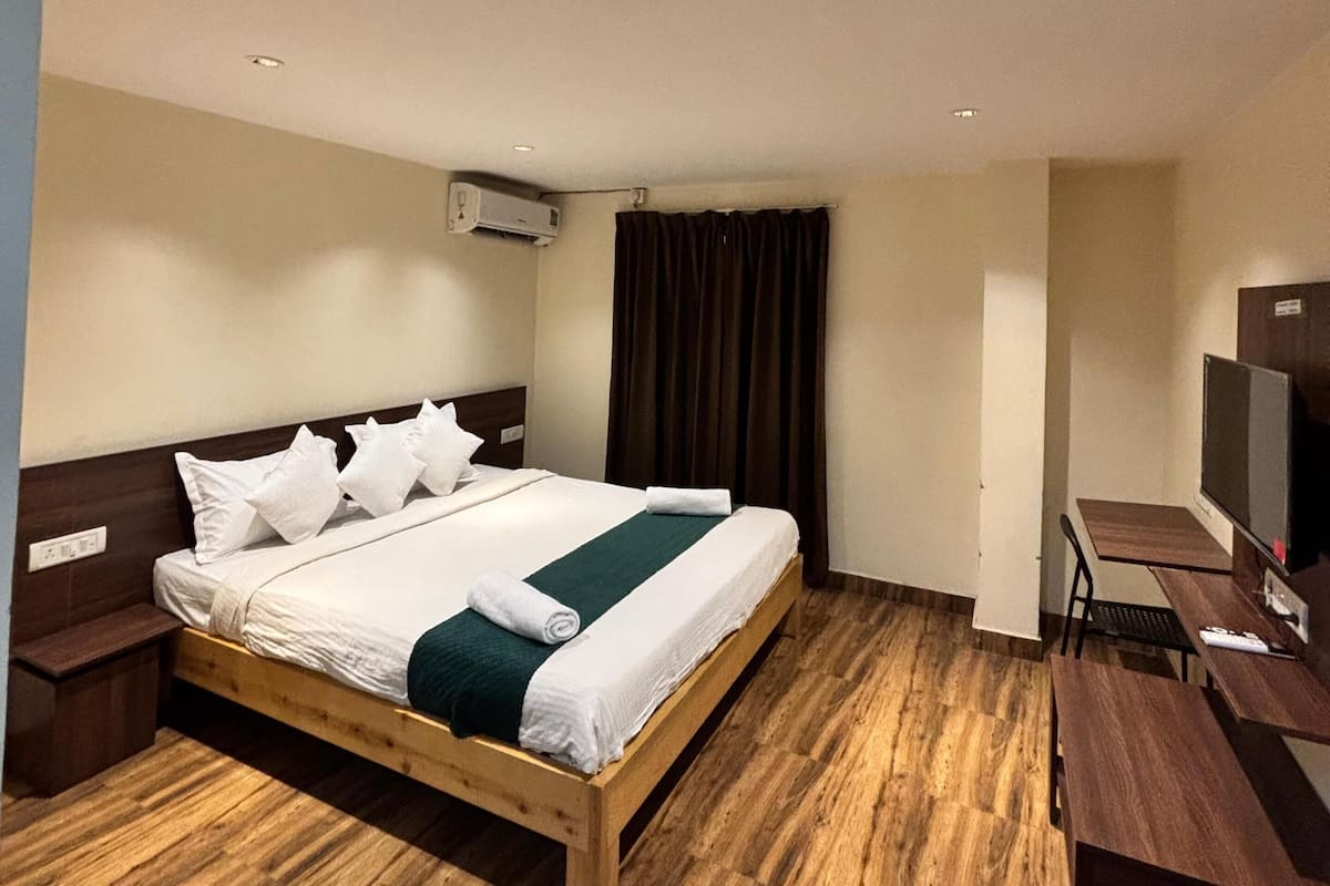Una habitación de hotel con una cama de madera, un escritorio con una computadora y un televisor.