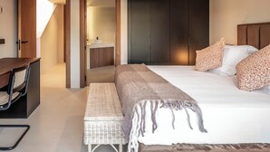 Ein modernes Schlafzimmer mit Bett, Nachttisch, Stuhl und integriertem Schreibtisch.
