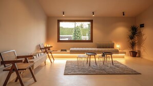 Ein modernes Wohnzimmer mit großem Fenster, einer Couch, einem Couchtisch und einem Essbereich mit Stühlen.