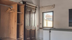 Ein Zimmer mit einem Holzschrank, einem großen Spiegel und einem Fenster mit Blick. Auf dem Bett liegen gestapelte Handtücher.