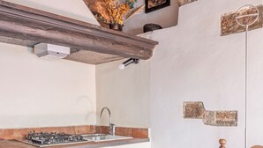Eine rustikale Küche mit sichtbaren Holzbalken, einer Ziegelwand und einem Gasherd.