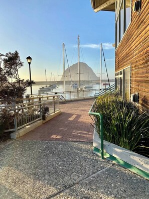 A waterfront walkway with a wooden building on the right, a clear view of boats and a mountain in the background. - Entire 2 Unit Duplex, King Beds, Rock View EV (Morro Bay)