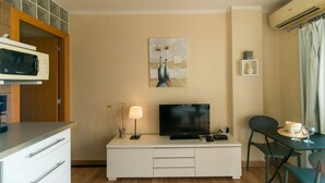 A modern living room with a flat-screen TV, a dining table with chairs, a microwave, and a cabinet. - WELCS STUDIO 294 EMP with sea view (Empuriabrava)