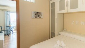 A hotel room with a bed, a desk, and a chair. There is a window with curtains, a wall-mounted artwork, and a wardrobe with the word "ZEN" on it. - WELCS STUDIO 294 EMP with sea view (Empuriabrava)