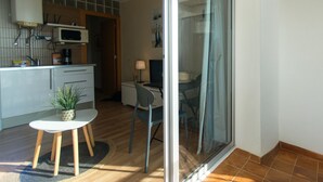 A modern kitchen with a microwave, sink, and cabinets, a dining area with a table and chairs, and a sliding glass door leading to a balcony. - WELCS STUDIO 294 EMP with sea view (Empuriabrava)