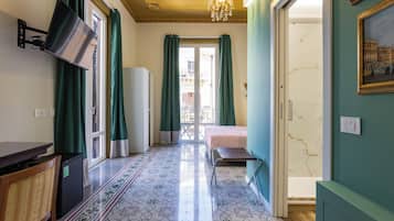 Une chambre d’hôtel avec un lit, un bureau, une chaise, un téléviseur fixé au mur et un sol à motifs.