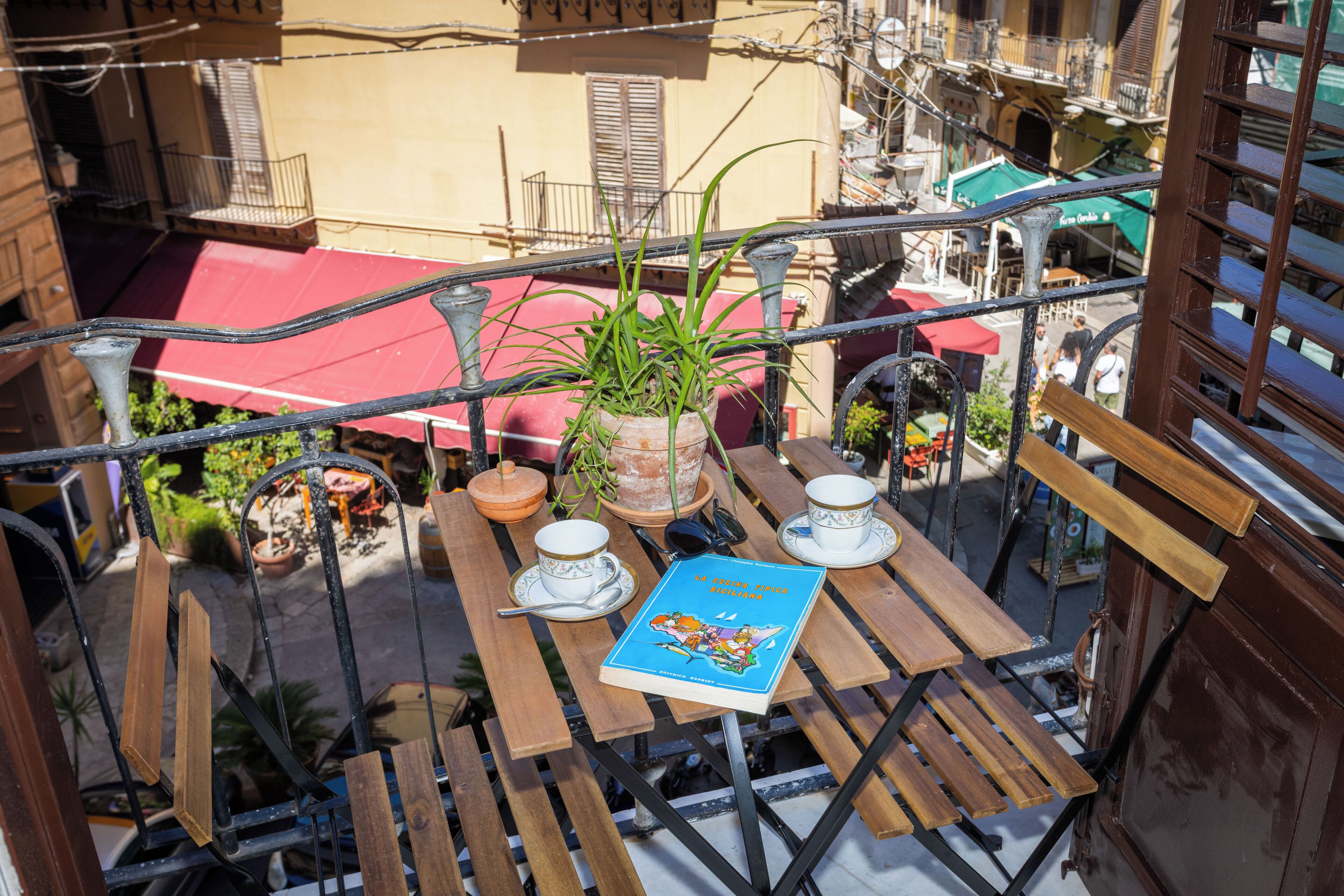 Ein Balkon mit Holztisch, Topfpflanze und Buch.