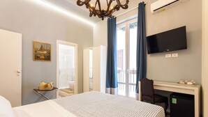 Ein Hotelzimmer mit Bett, Schreibtisch, Fernseher und kleinem Kühlschrank.