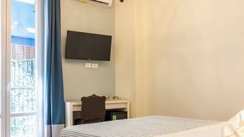 A hotel room with a bed, a desk, a television, and a chandelier.