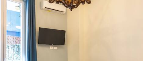 A hotel room with a bed, a desk, a television, and a chandelier.
