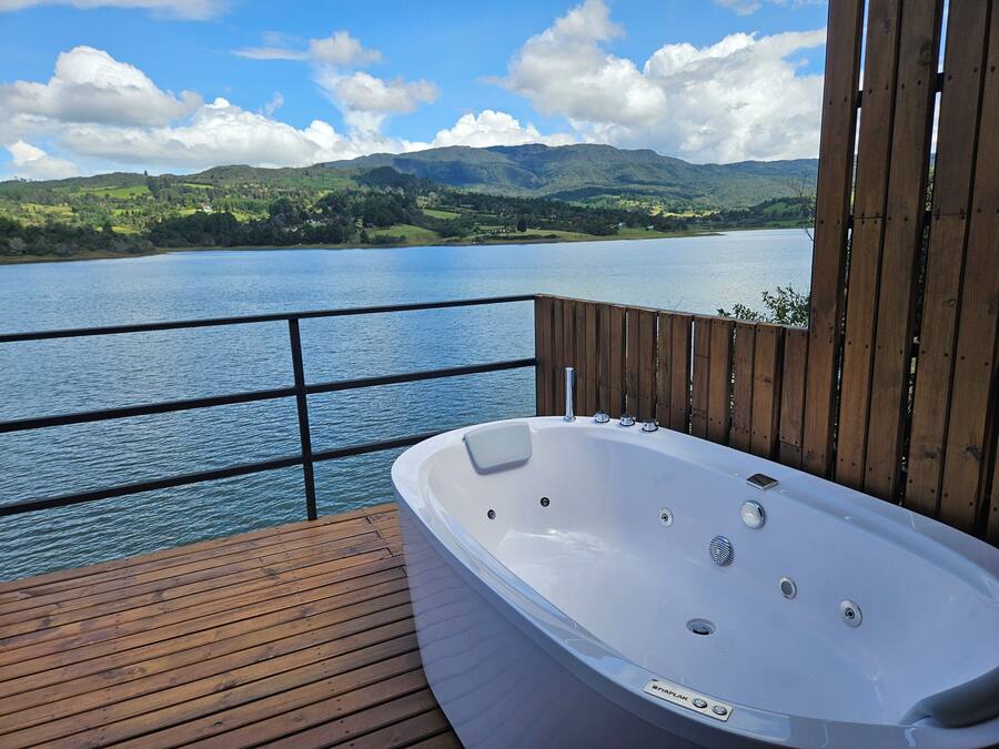 Une terrasse en bois avec un jacuzzi donnant sur un lac et des montagnes.